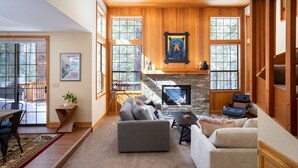 A spacious living room with a stone fireplace, large windows, and a cozy seating area.