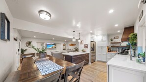 Een moderne keuken met witte kastjes, een houten eettafel en een centraal kookeiland.