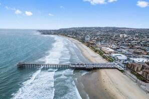 A coastal cityscape with a long pier extending into the ocean, adjacent to a sandy beach and residential buildings. - Dream vacation beach house - 1 min. walk to Pacific Beach & Garnet Avenue (San Diego)