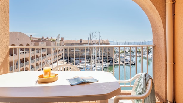 A balcony with a table, chairs, and a view of a marina with boats. - Résidence Pierre & Vacances Hyeres Le Port (Hyères)