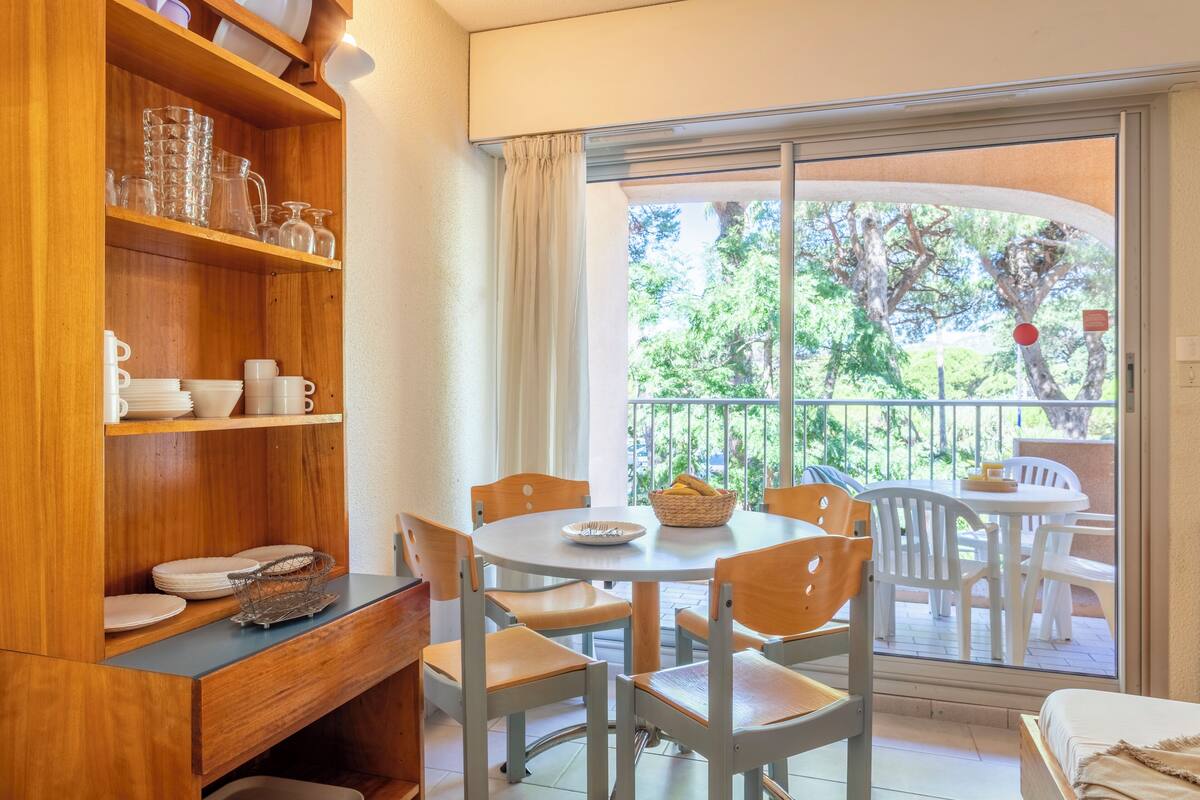 Ein Essbereich mit einem runden Tisch, Stühlen und einem Holzsideboard mit Geschirr.