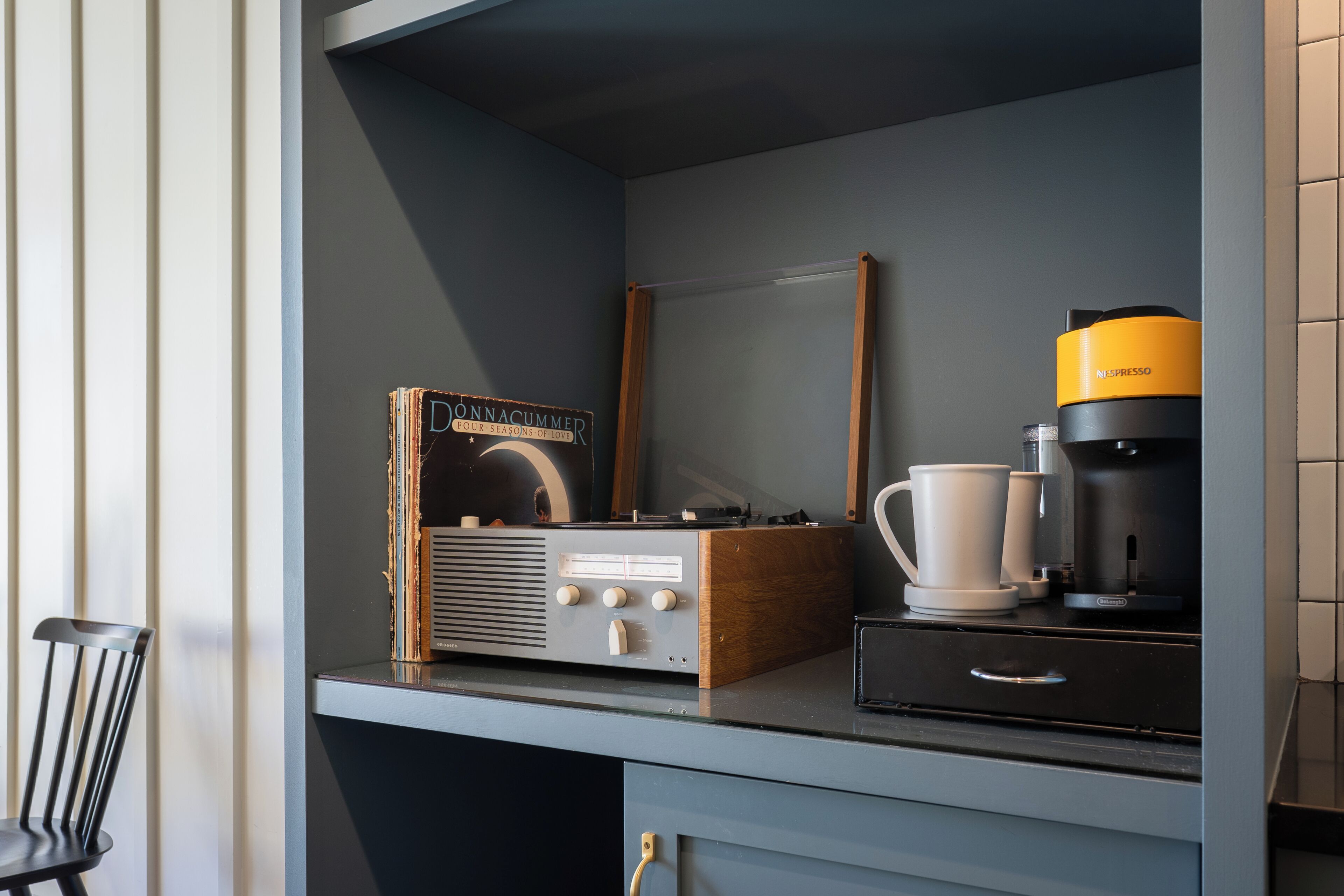 Una kitchenette con una cafetera, una radio antigua y una taza de café.