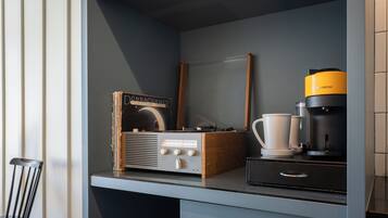 Una kitchenette con una cafetera, una radio antigua y una taza de café.