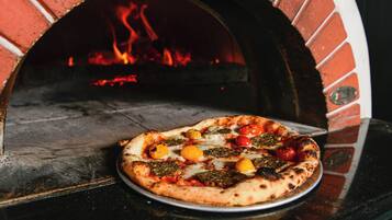 A pizza in a brick oven with visible flames.