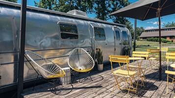 A vintage trailer with a dining area featuring yellow chairs and tables.