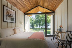 Un dormitorio con una cama grande, vistas a un lago y un comedor con mesa y sillas.