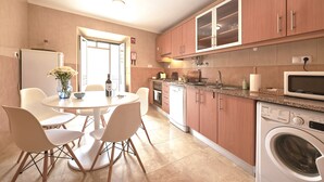 A modern kitchen with a dining area, including a round table, chairs, and a built-in washing machine. - Idyllic Lisbon Apartments With Amazing Courtyard (Lisboa)