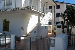 A multi-story building with a central staircase, balconies, and a gated entrance. - M116 - Marcelli, two-room apartment in the center and facing the sea (Marcelli)