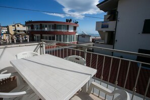A balcony with a white table and chairs, a red building in the background, and a clear sky. - M116 - Marcelli, two-room apartment in the center and facing the sea (Marcelli)
