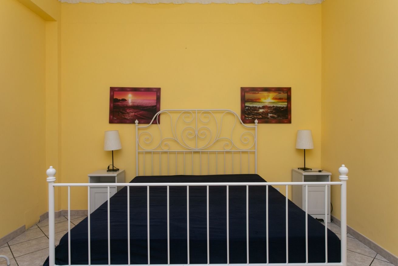 A room with a bed, two bedside tables, and two wall-mounted lamps.