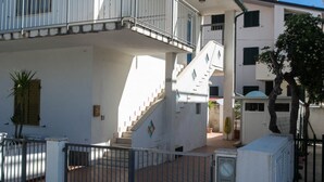 A multi-story building with a central staircase, balconies, and a gated entrance. - M116 - Marcelli, two-room apartment in the center and facing the sea (Marcelli)