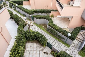 Un espacio al aire libre con varios niveles, senderos, vegetación y una escalera.