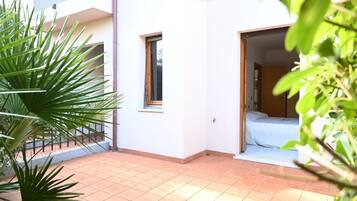 A small, enclosed outdoor area with a tiled floor, a window, and a door leading to a bedroom.