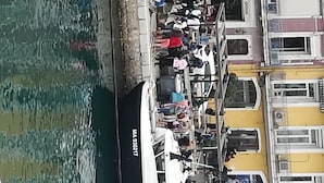 Ein belebter Uferbereich mit einem großen weißen Boot, das an einem Steg festgemacht ist.