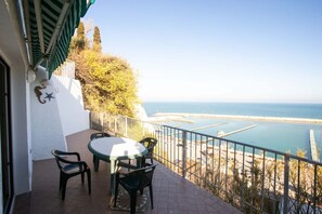 Ein Balkon mit Tisch und Stühlen mit Blick auf eine Küstenlandschaft und einen Steg.