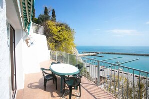 A balcony with a table and chairs, overlooking a marina with boats and a clear blue sky. - N033 - Numana, two-room apartment with wonderful terrace overlooking the sea (Numana)