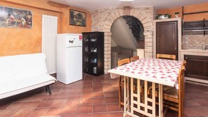 Una cocina compacta con zona de comedor, un refrigerador, un mueble negro y piso de baldosas.