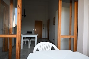 A room with a white table and chairs, wooden beams, a door, and a hanging light fixture.