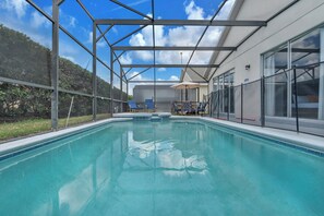 An indoor swimming pool with a covered area, clear blue water, and a view of the surrounding landscape.