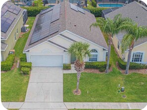 A residential area with houses, solar panels, a palm tree, and a swimming pool.