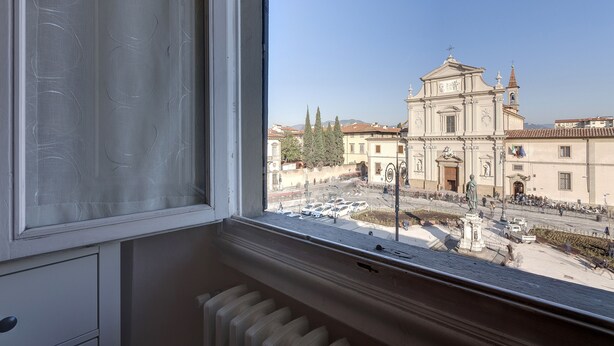 A window view of a building with classical architecture, including a bell tower and statues.