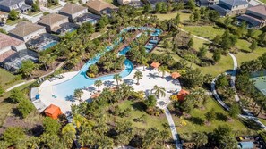 Luchtbeeld van een resort met een centraal zwembad, omgeven door palmbomen en loungegedeeltes.