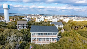 Zona residencial costera con varias casas, un alto tanque de agua y vista al mar.