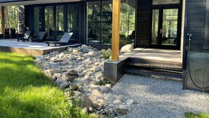 Une maison moderne dotée d’un patio couvert, d’un espace salon extérieur et d’un chemin en gravier.