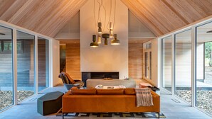 Un intérieur moderne avec un plafond haut, une cheminée, un canapé et de grandes fenêtres.