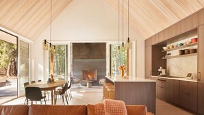 Un vaste espace de vie doté d’une cheminée, d’un plafond en bois et d’une cuisine avec des plans de travail en marbre.