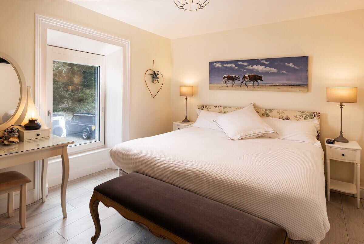 A bedroom with a bed, bedside tables, a desk, and a bench.