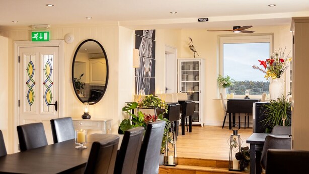A dining area with a long table, chairs, and a view of the outdoors. - Manse On The Beach (Portaferry)
