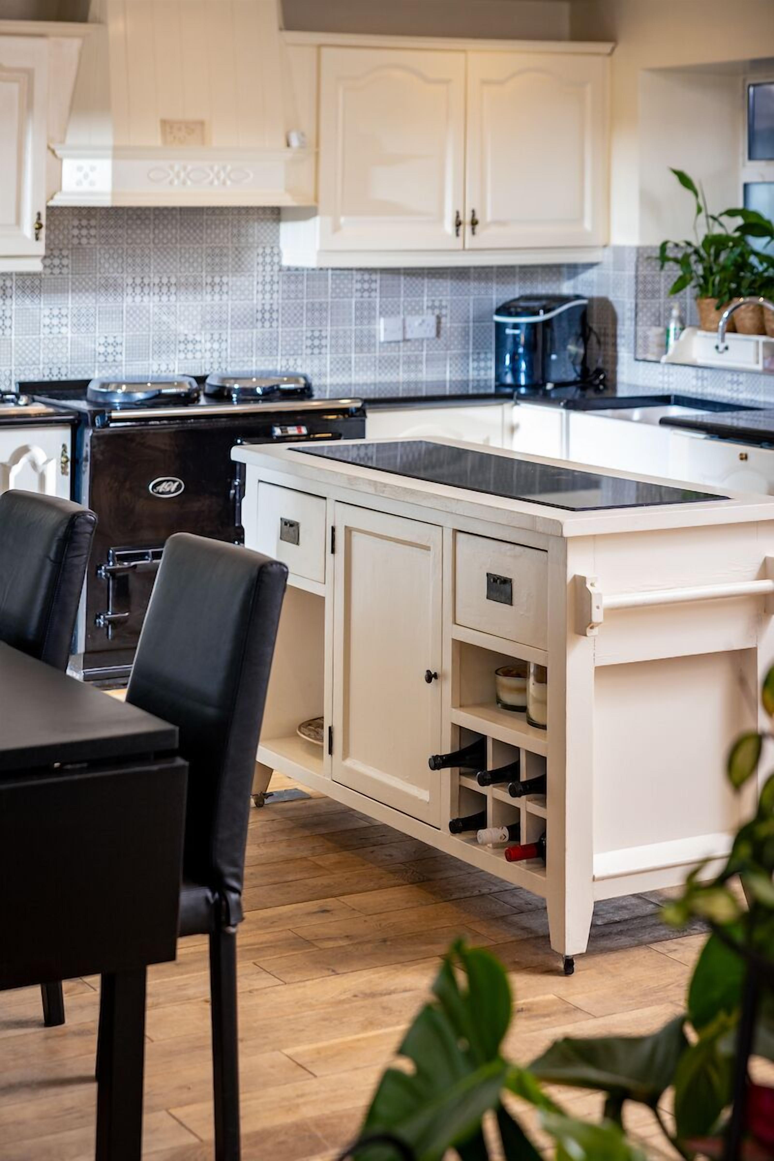 A modern kitchen with white cabinetry, a black countertop, and a built-in wine rack.