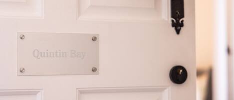 A white door with a nameplate reading "Quintin Bay" and a black door handle.