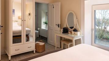 Un dormitorio con cama, armario de puertas de cristal, escritorio con espejo y vistas al exterior.