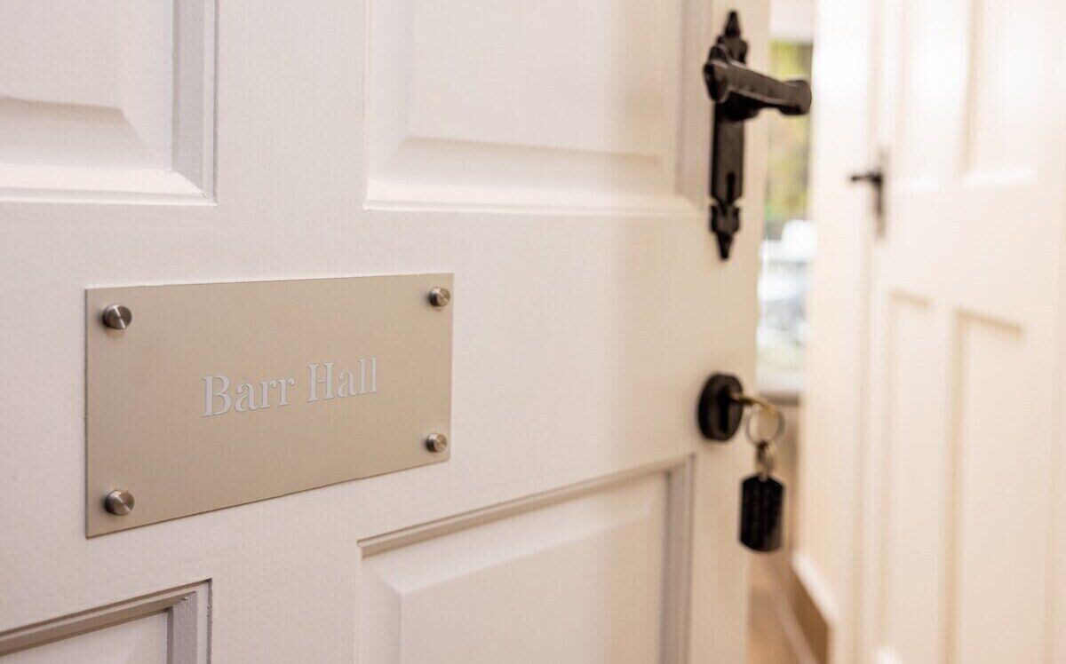 A white door with a metal plate labeled "Barr Hall".