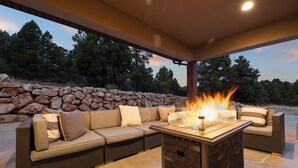 An outdoor seating area with a stone wall, a fire feature, and a covered patio. - Spacious, Private Hot Tub, 6 bedrooms 5 Ensuite Bathrooms. 7th night FREE!  (Orderville)