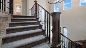 A carpeted staircase with a wooden railing and a chandelier. - Spacious, Private Hot Tub, 6 bedrooms 5 Ensuite Bathrooms. 7th night FREE!  (Orderville)