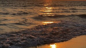 Un atardecer sobre el océano con olas llegando a la orilla.