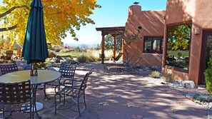 An outdoor patio with stone flooring, metal furniture, and a green umbrella.