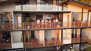 A modern multi-story building with a balcony area where people are standing. - Award Wining Ocean View Villa - Walk to Beach (Santa Teresa)