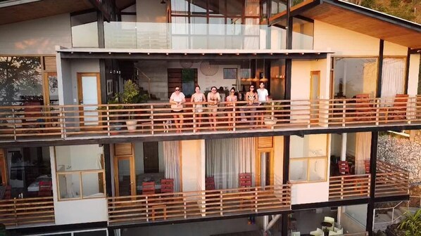 A modern multi-story building with a balcony area where people are standing.