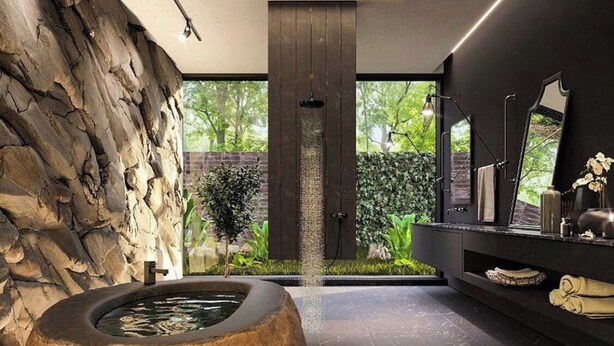 A modern bathroom with a stone wall, a circular hot tub, a shower area, and a vanity with a mirror and toiletries. - Award Wining Ocean View Villa - Walk to Beach (Santa Teresa)