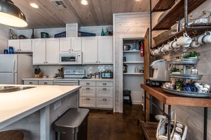 A modern kitchen with white cabinetry, a built-in oven, a microwave, and a stainless steel sink.