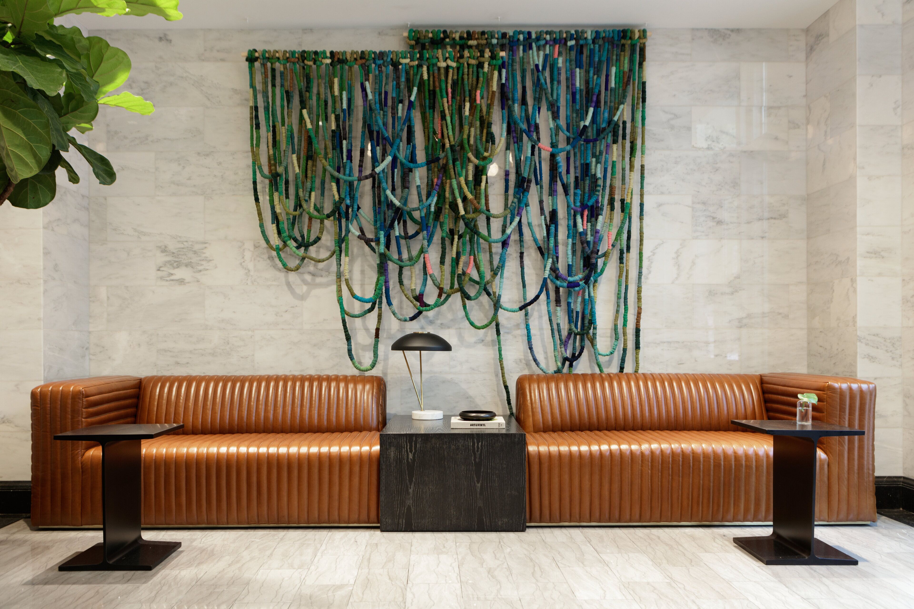 A modern lobby with a leather sofa, a coffee table, and a wall art installation.