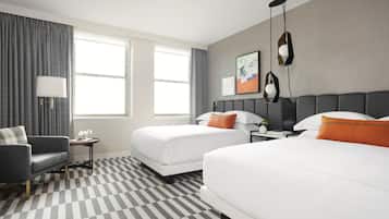 A hotel room with two beds, a sofa, a small table, and a lamp.