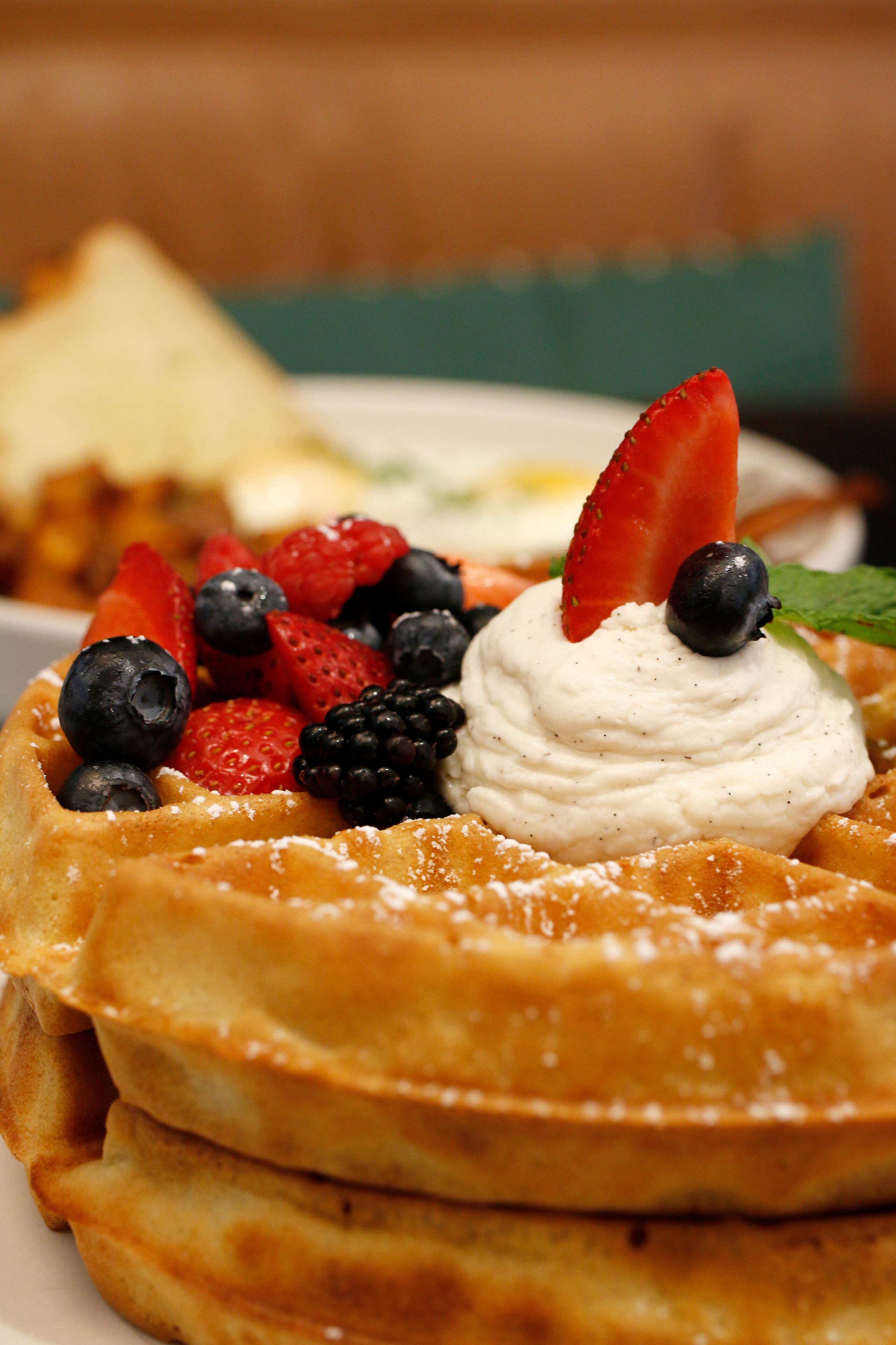 A stack of waffles topped with whipped cream, strawberries, blueberries, and blackberries.