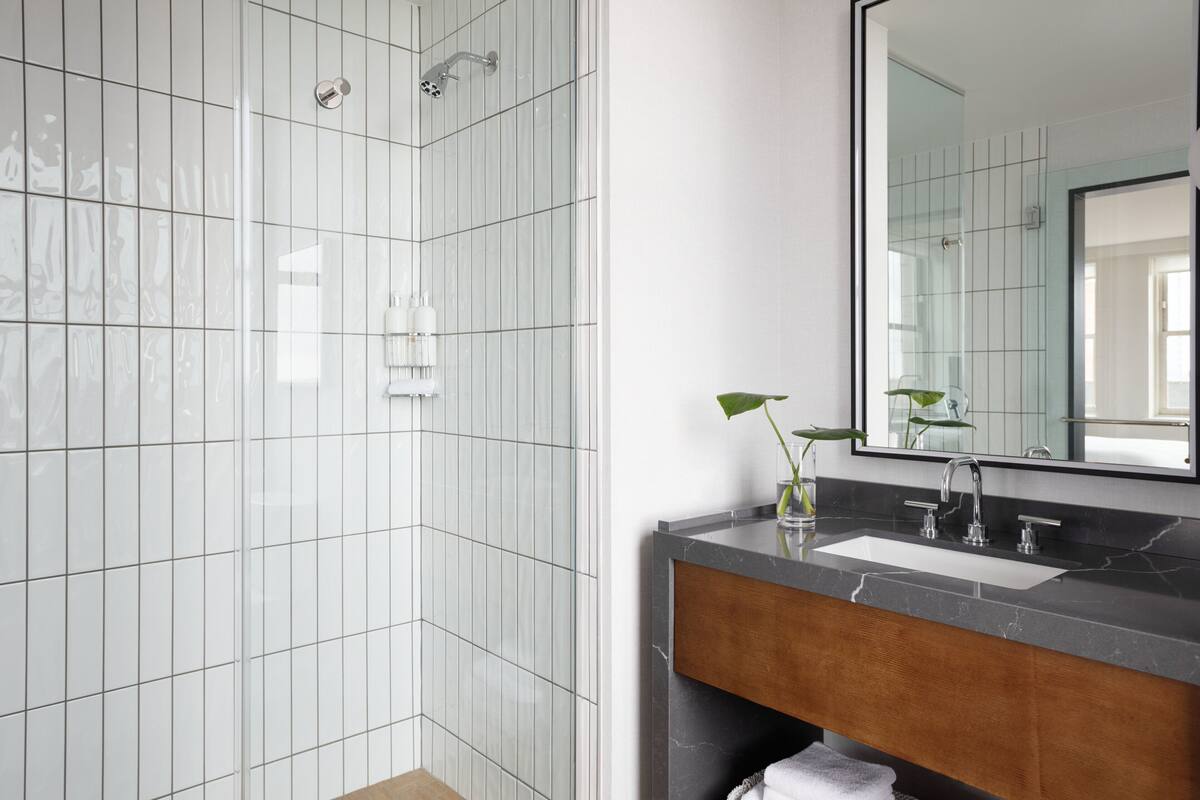 A modern bathroom with a glass shower enclosure, a marble sink, and a large mirror.