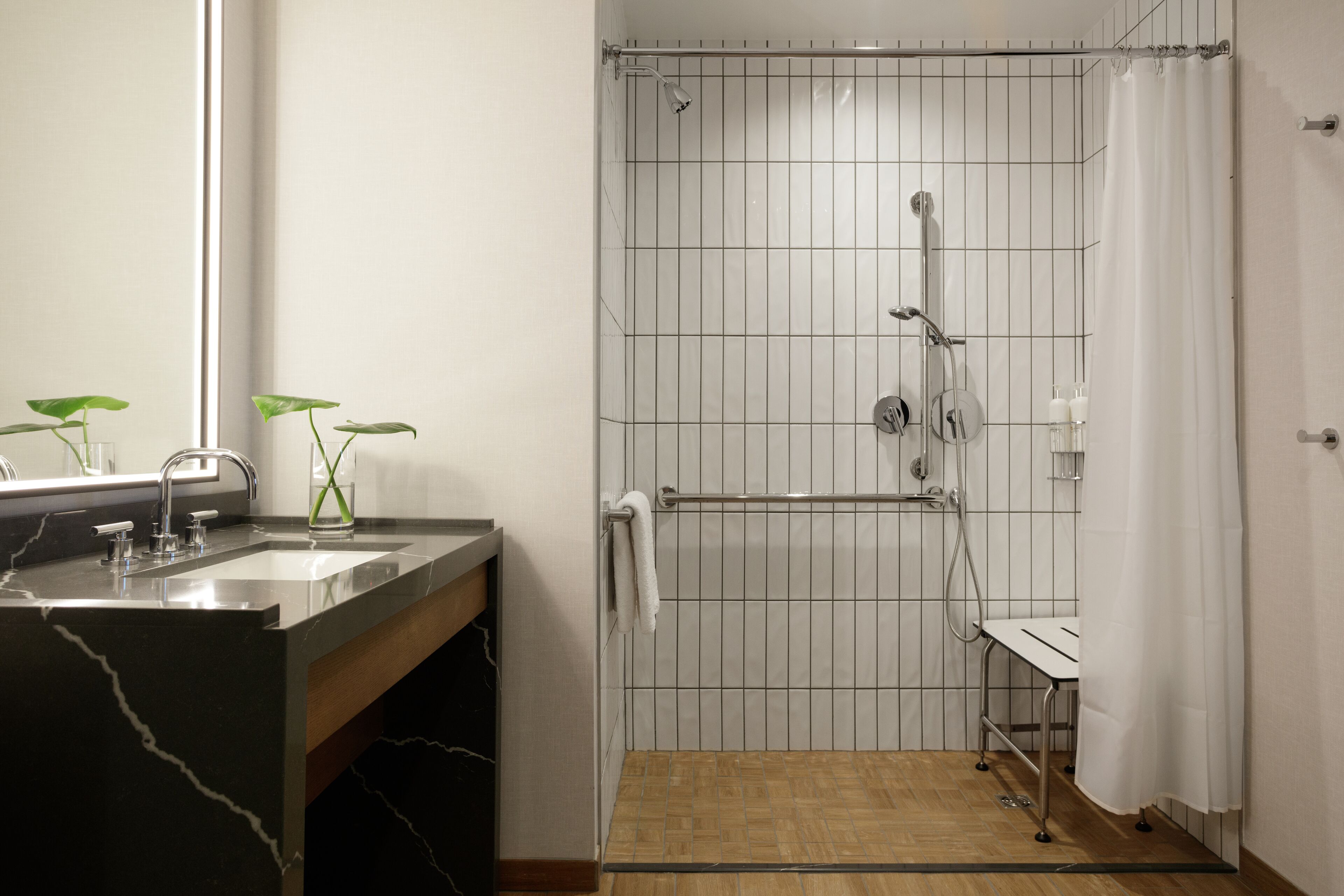Een badkamer met een douche, wastafel en spiegel.