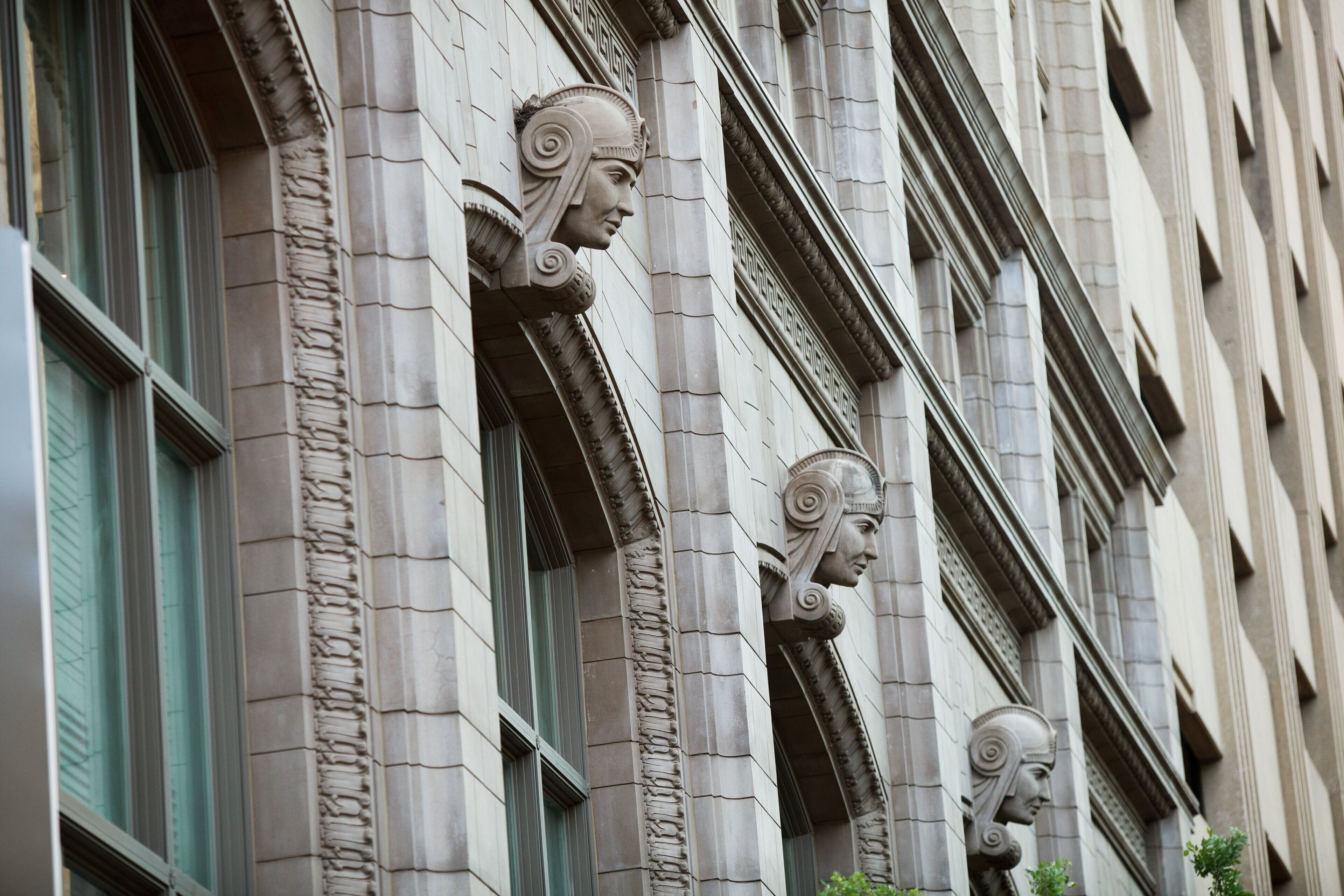 Facciata di un edificio con elementi architettonici classici, tra cui elaborate decorazioni in pietra e ampie finestre.